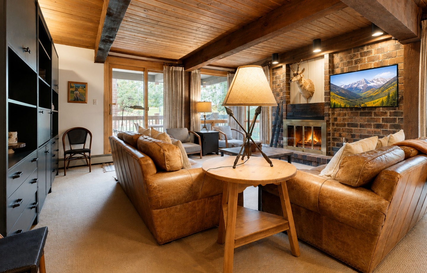 Sink into plush leather seating beside a crackling fire, with mountain views warming your stay beneath rustic wood beams and cozy ambient lighting.