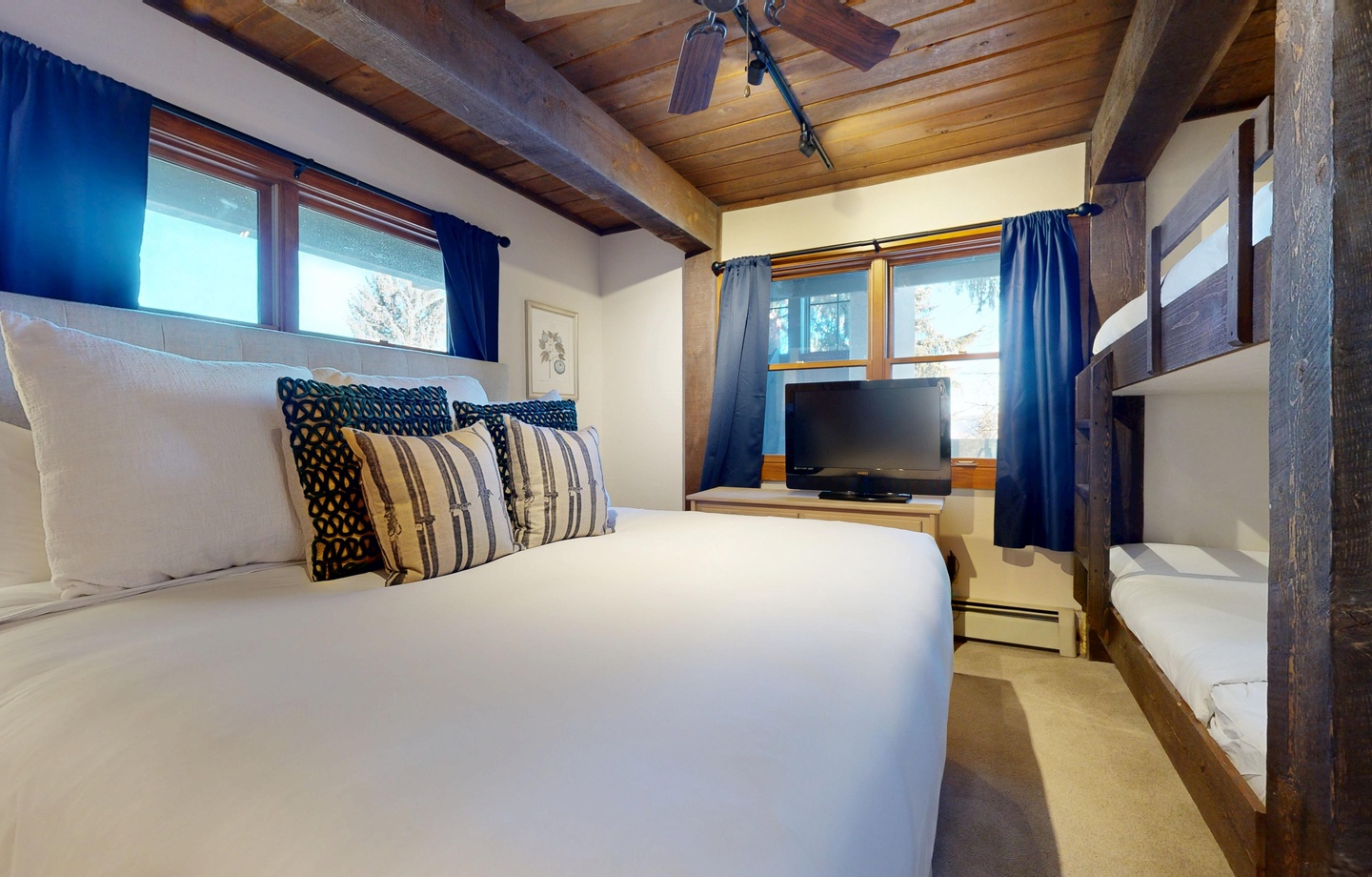 Cozy up in your rustic bedroom with exposed wooden beams, crisp white linens, and charming blue accents that create the perfect mountain retreat atmosphere.