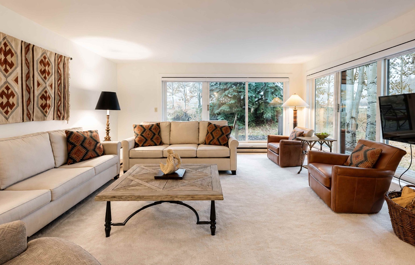 Your spacious living room features plush sofas, warm leather accents, and large windows flooding the space with natural light and peaceful garden views.