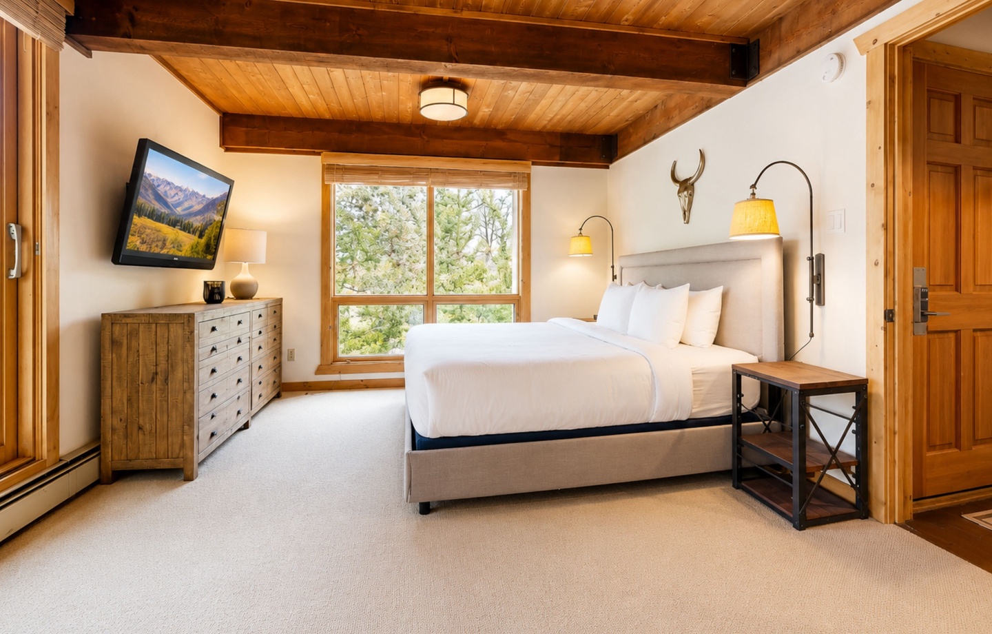 Wake up in this cozy mountain bedroom where warm wood beams frame your peaceful retreat. Crisp linens await you on a plush bed, while natural light streams through windows revealing stunning forest views from your private escape.