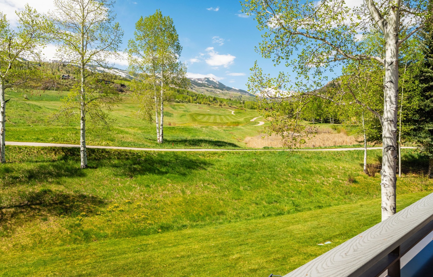 The property features sweeping views across an adjacent golf course, framed by aspen trees and distant mountain peaks, offering a peaceful mountain setting for guests.
