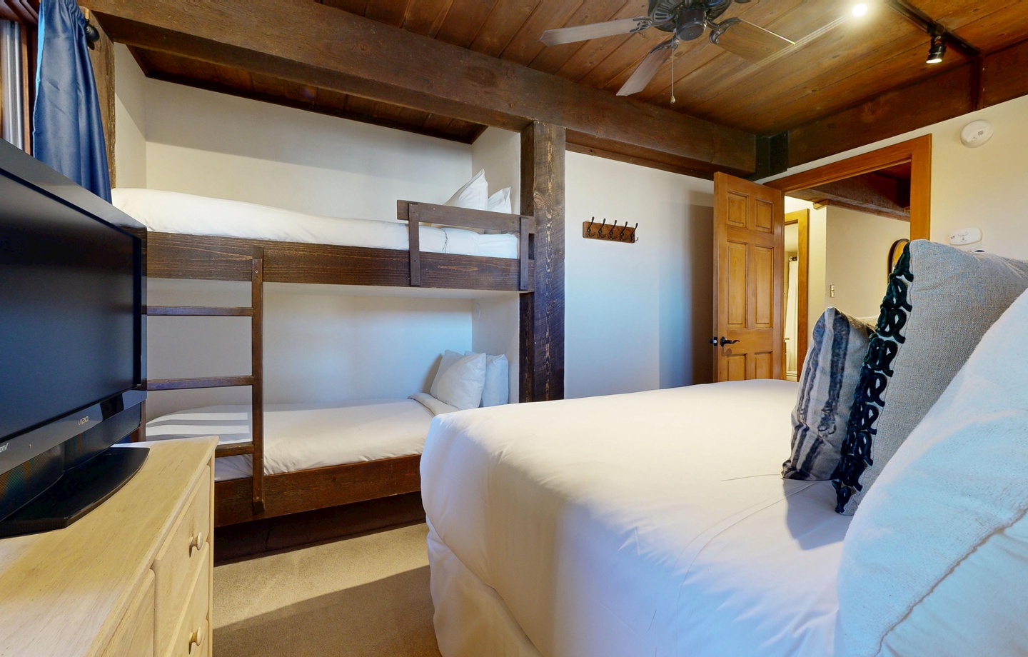 Sink into crisp linens while rustic beams and a ceiling fan create your cozy mountain retreat atmosphere.