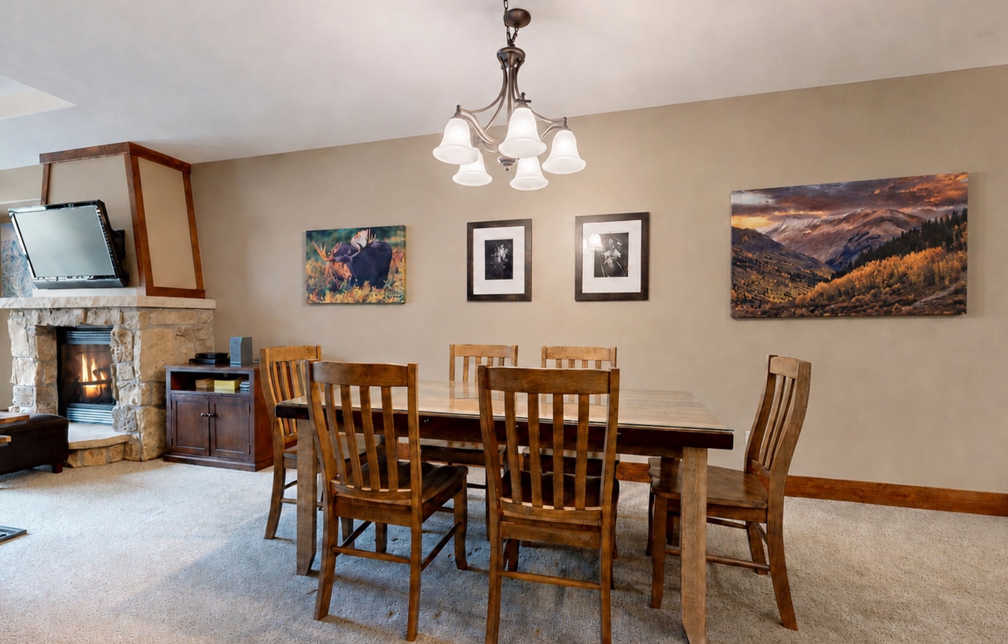 Gather around this inviting dining table where your group can share meals and stories. The warm glow of the fireplace and mountain-inspired artwork set the scene for memorable evenings together.
