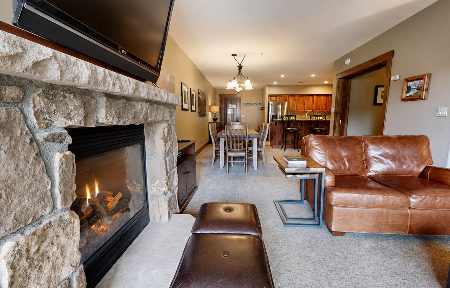 Unwind in your inviting living space, where a crackling stone fireplace creates the perfect ambiance for cozy evenings. Rich leather furnishings and an open layout seamlessly connect you to the dining area and fully equipped kitchen beyond.