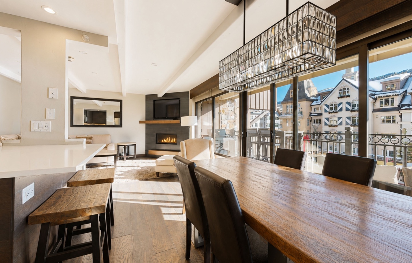 Sunlight streams through expansive windows onto rich wood floors and a cozy fireplace, creating the perfect spot for your mountain retreat. Vaulted ceilings and stunning views of the alpine village complete your ideal escape.