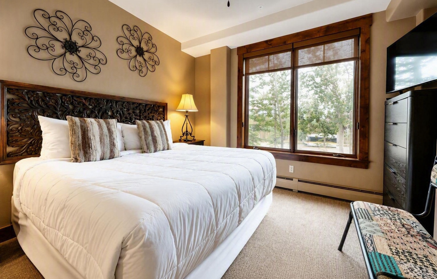 Sink into crisp linens in your peaceful bedroom retreat. The handcrafted headboard and warm lighting create an inviting ambiance, while your window frames natural views to greet you each morning.