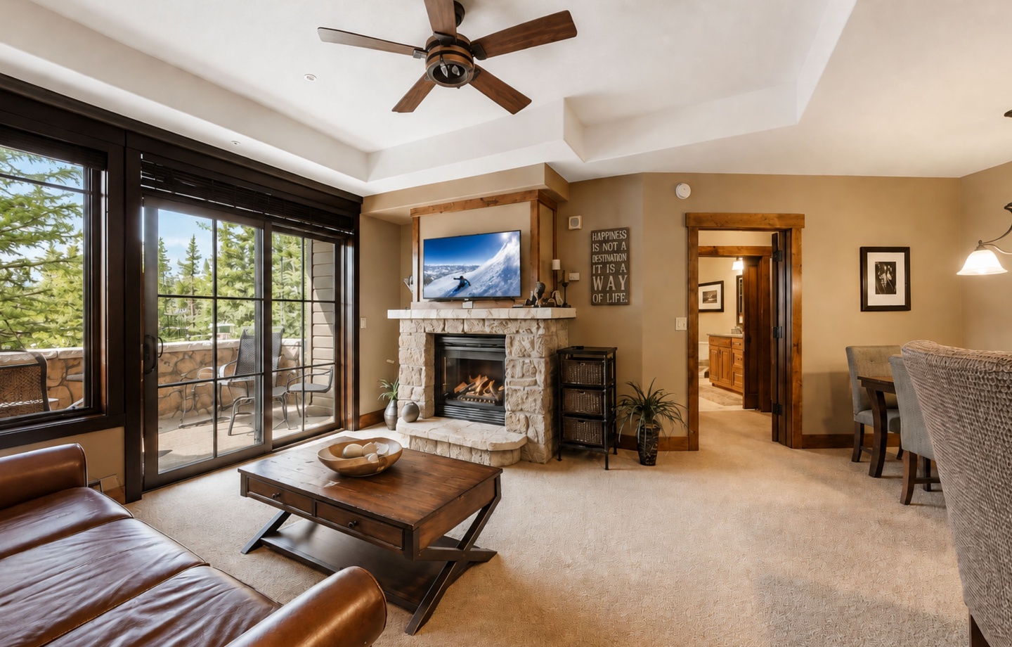 Relax in your spacious living room where mountain air flows through balcony doors and warm firelight dances on stone, creating the perfect alpine retreat for cozy evenings.