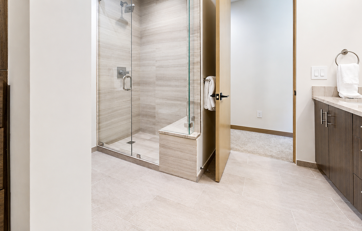 Step into your private spa-like bathroom with a spacious glass-enclosed shower and elegant wood-grain finishes throughout.