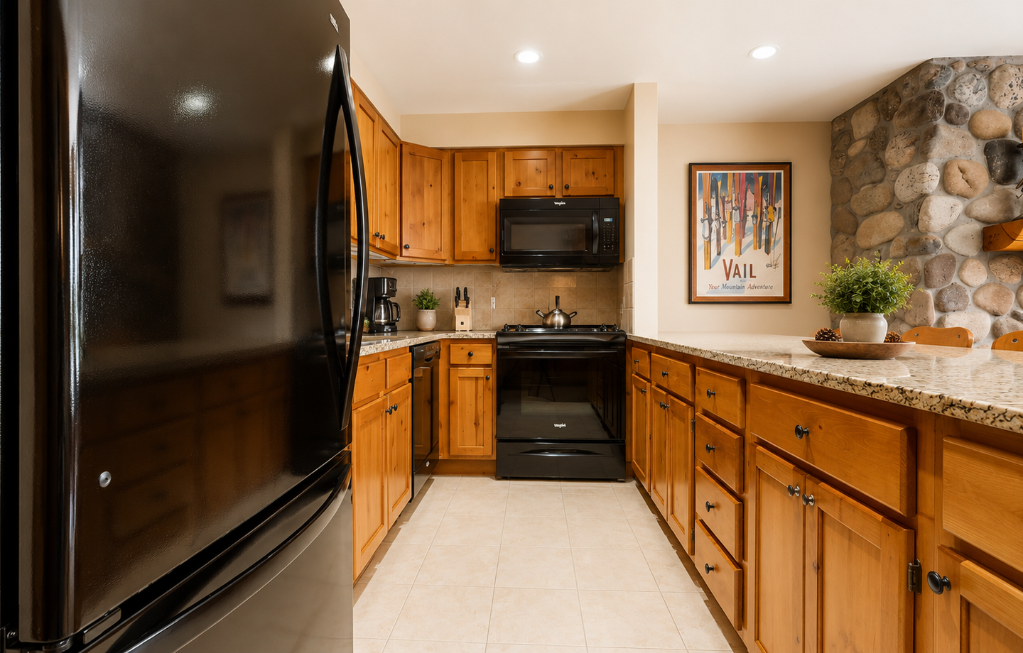 Cook your favorite meals in this fully equipped kitchen with modern appliances, warm wood cabinetry, and charming stone accent wall—your mountain home away from home.