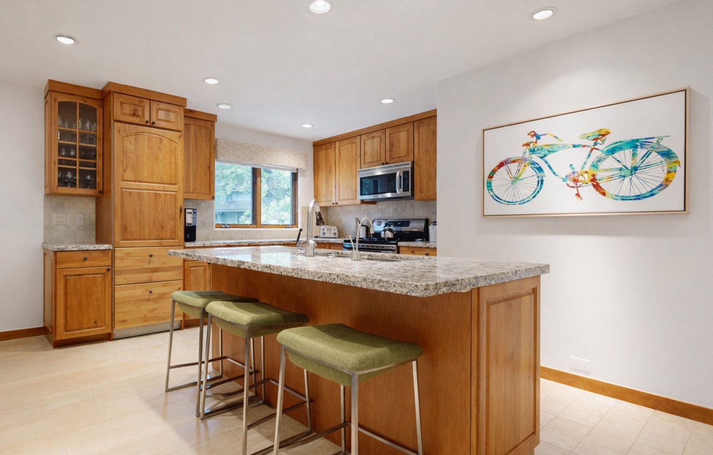 Your fully equipped kitchen features warm wood cabinets, granite counters, and a breakfast bar perfect for morning coffee or casual dining together.