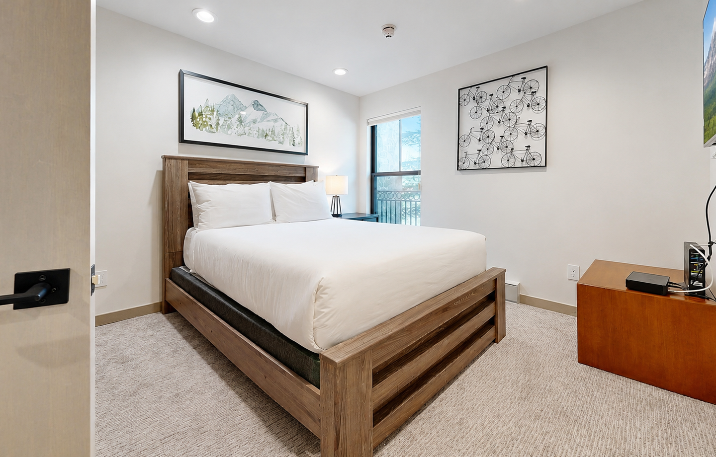 Rest easy in your serene bedroom, where crisp white linens and modern wood furnishings create a peaceful retreat after a day of adventure.