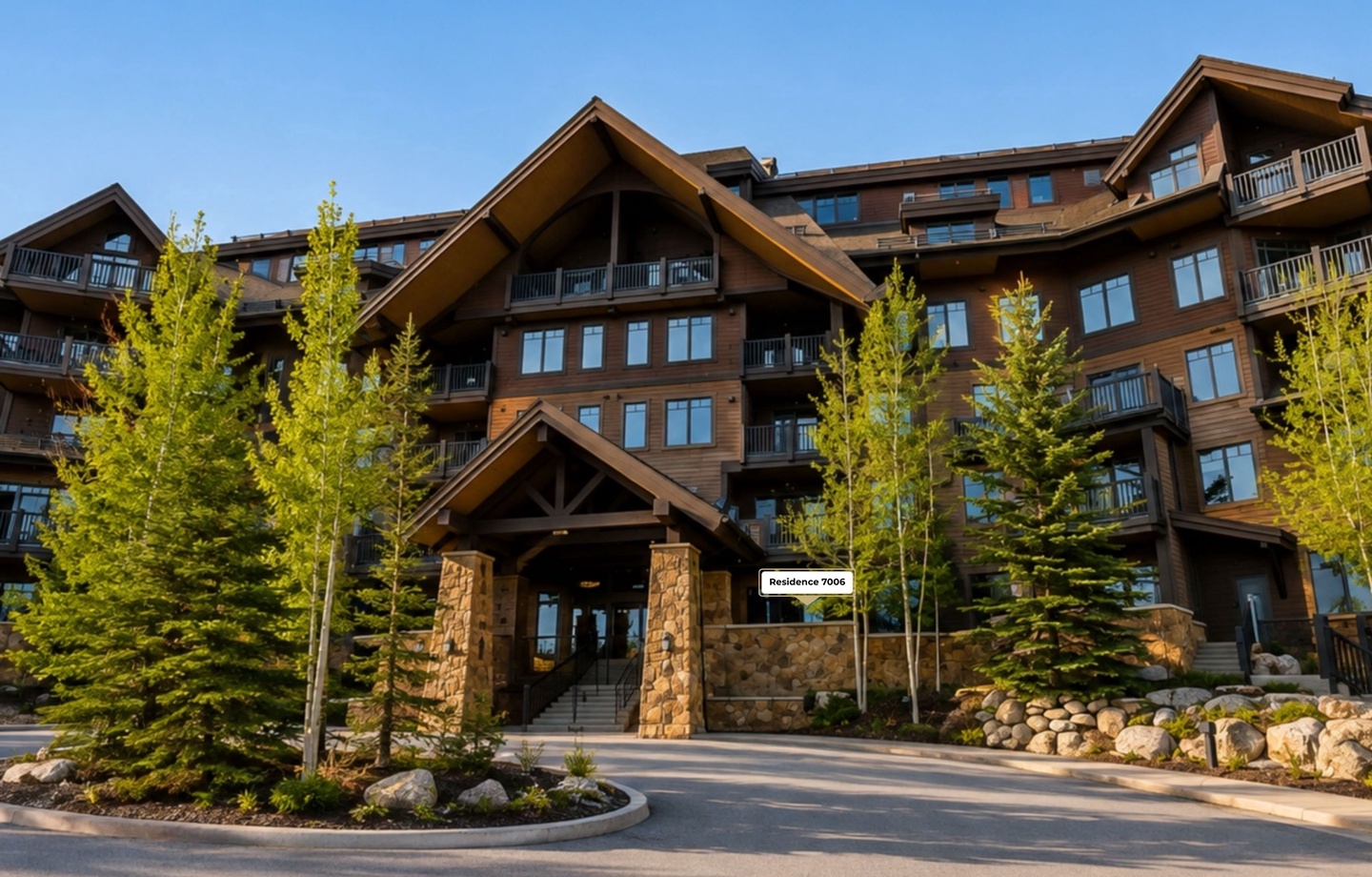 A striking mountain lodge-style residence with warm timber architecture, stone accents, and beautifully landscaped grounds welcomes arrivals with its impressive entrance and scenic alpine surroundings.