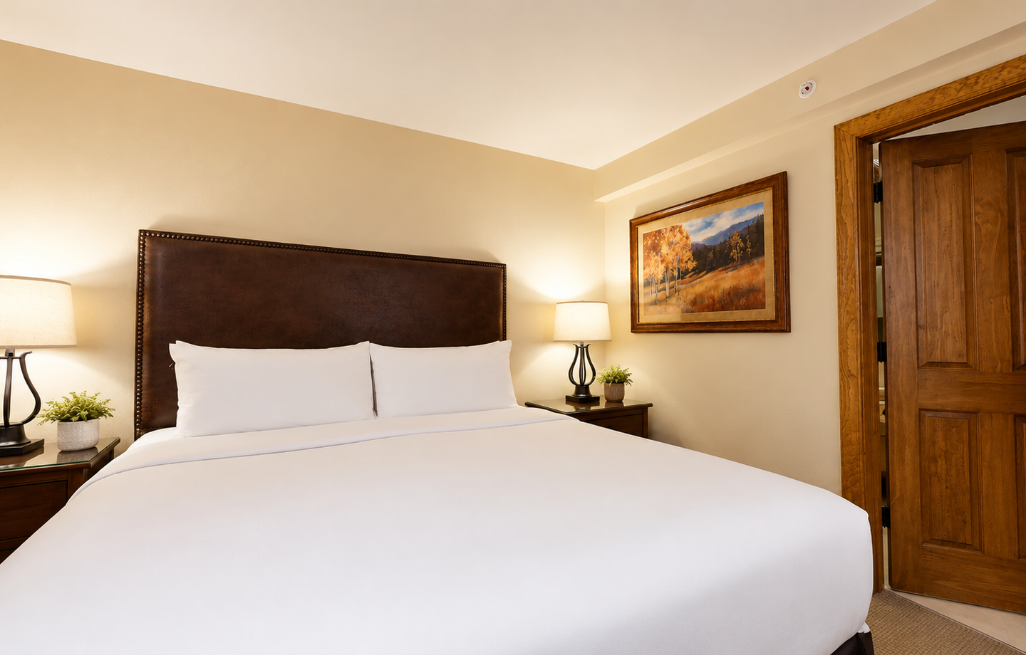 Sink into crisp white linens on your plush bed, framed by elegant wood furniture and soft lighting that invites restful sleep after your mountain adventures.