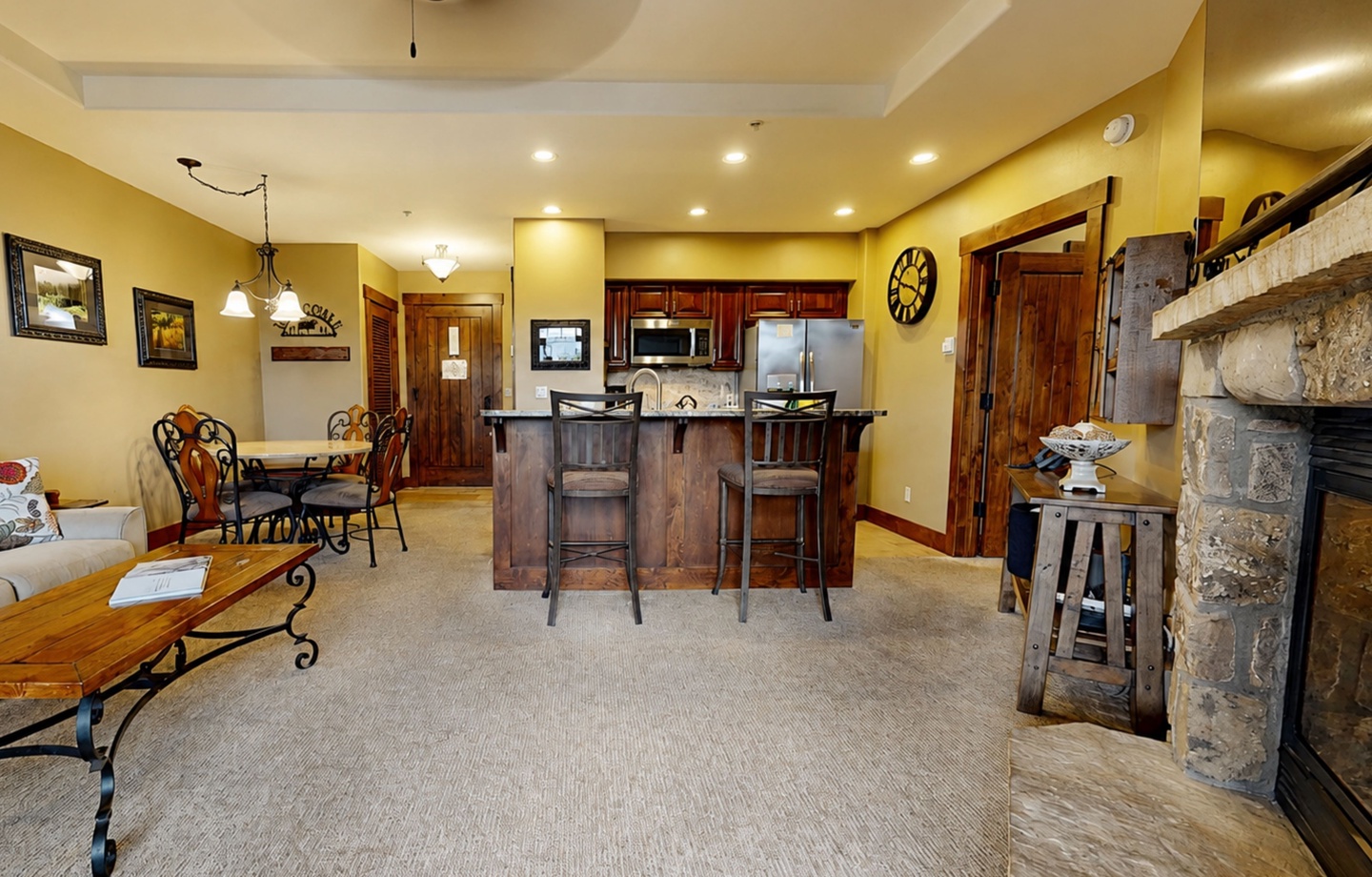 Open-concept living space with a fully equipped kitchen, stone fireplace, and cozy seating areas. Your perfect mountain retreat for unwinding and connecting.