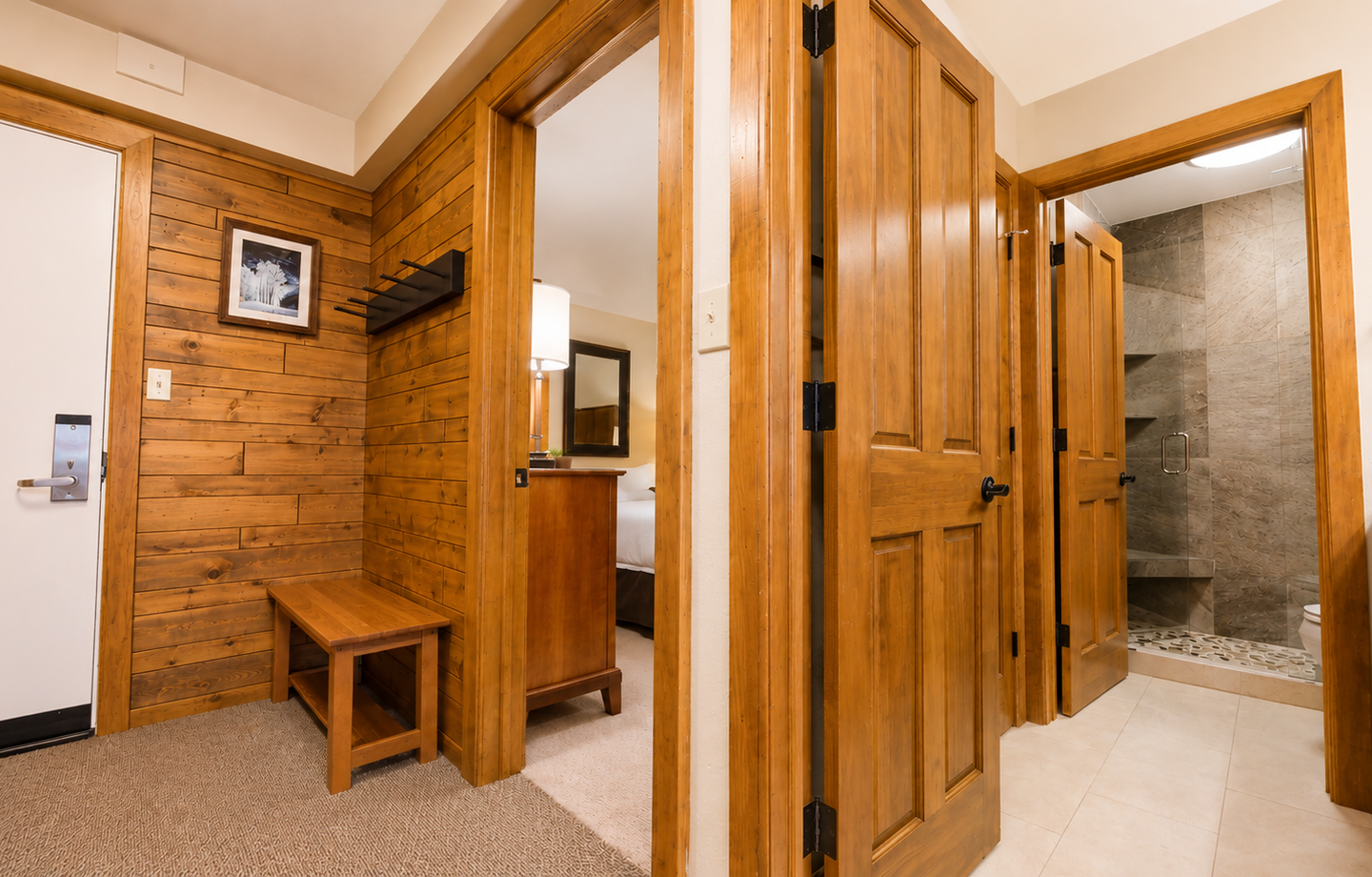 Step into your private retreat where warm wood accents and thoughtful design create a welcoming atmosphere. A spacious bathroom with stone-tiled shower awaits you through beautifully crafted doors.