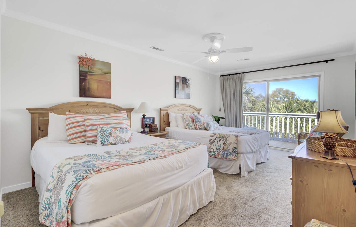 - Rest easy in this inviting bedroom featuring two plush queen beds and serene decor - Private balcony access lets you wake up to fresh air and peaceful green views - Coastal accents, soft carpet, and natural light make this room a guest favorite