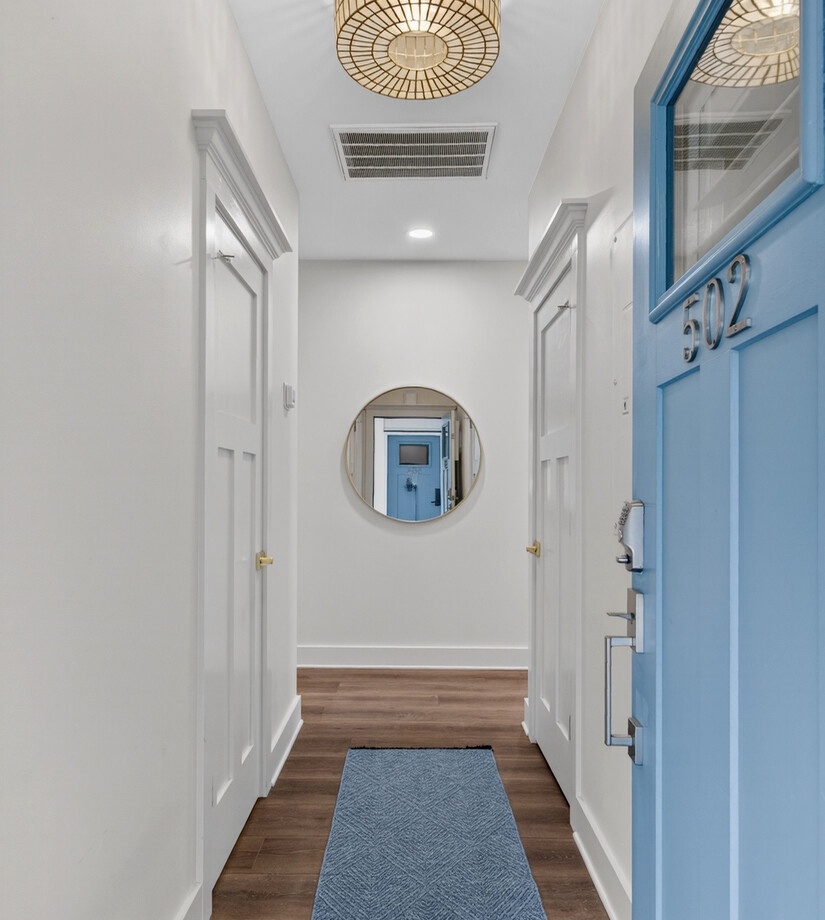 Step into your welcoming hallway with warm wood floors, coastal blue accents, and elegant ceiling lighting creating a serene entrance.