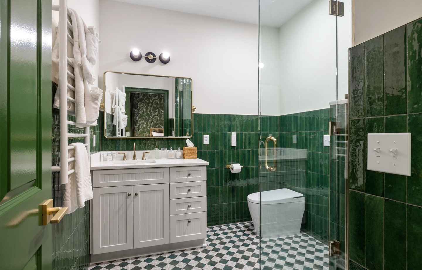 Step into your elegant emerald-tiled bathroom where classic checkered floors meet modern comfort and luxury touches await.