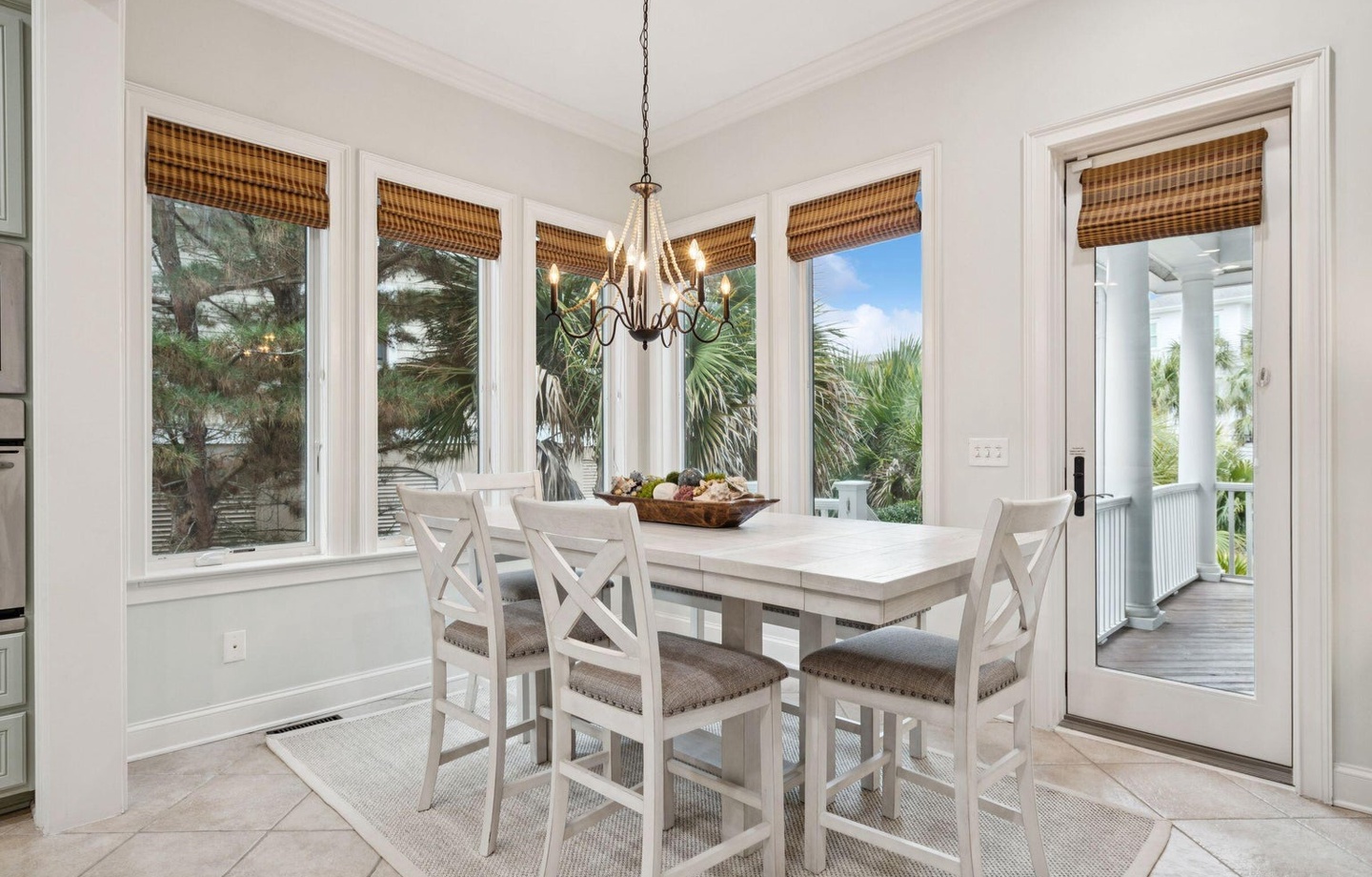 Gather around this bright dining nook where bamboo shades filter gentle light and tropical views create your perfect breakfast backdrop.