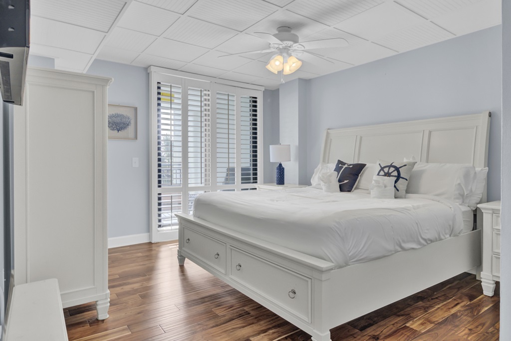 - Drift off in a plush king bed framed by crisp white furniture and soft blue walls - Natural light floods in through shuttered windows, creating a serene, beachy vibe - With extra drawer storage and peaceful decor, it’s the ultimate relaxation zone
