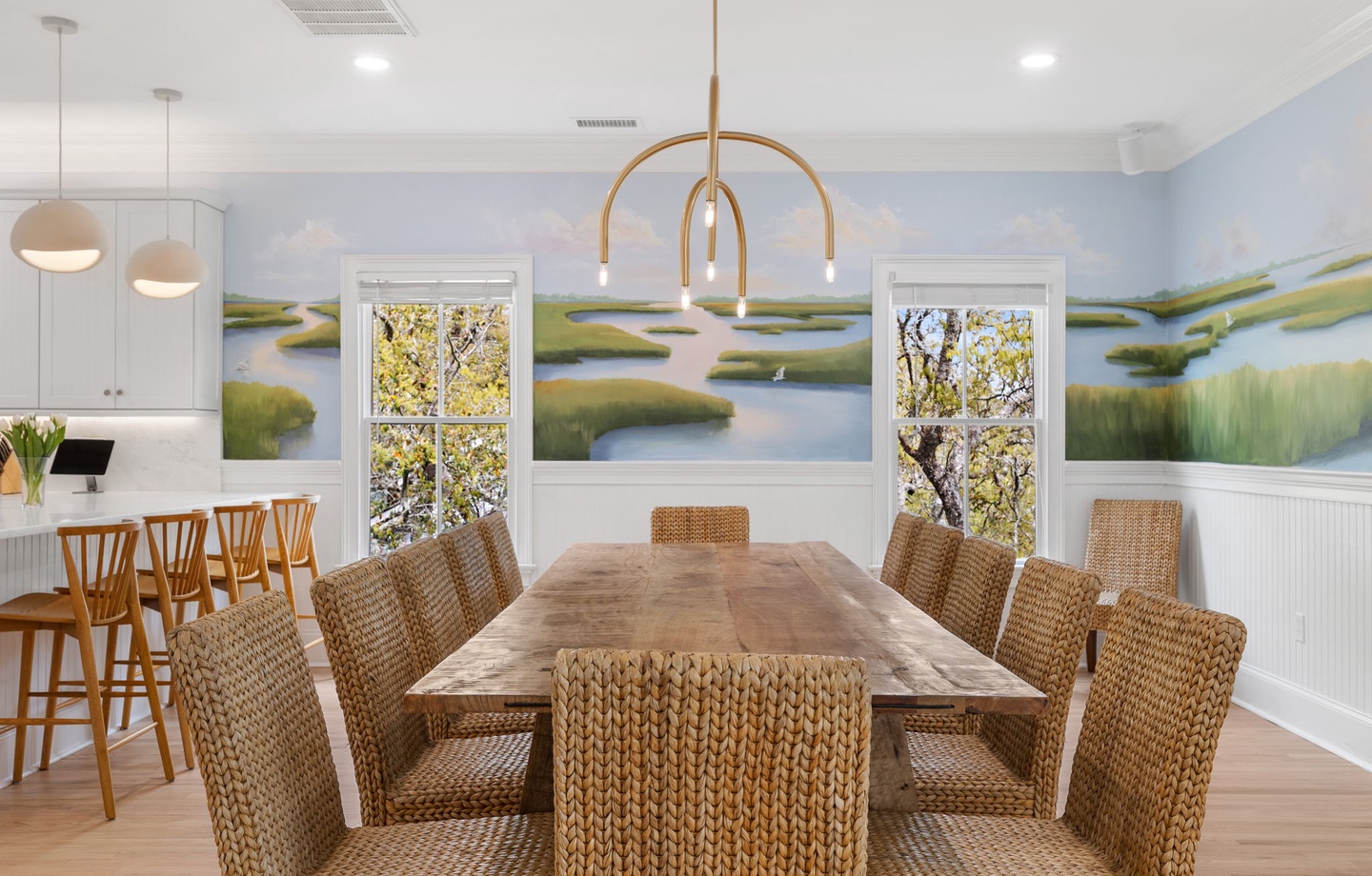 Gather around your dining table under modern lighting while beautiful marshland artwork creates a serene backdrop for memorable meals together.
