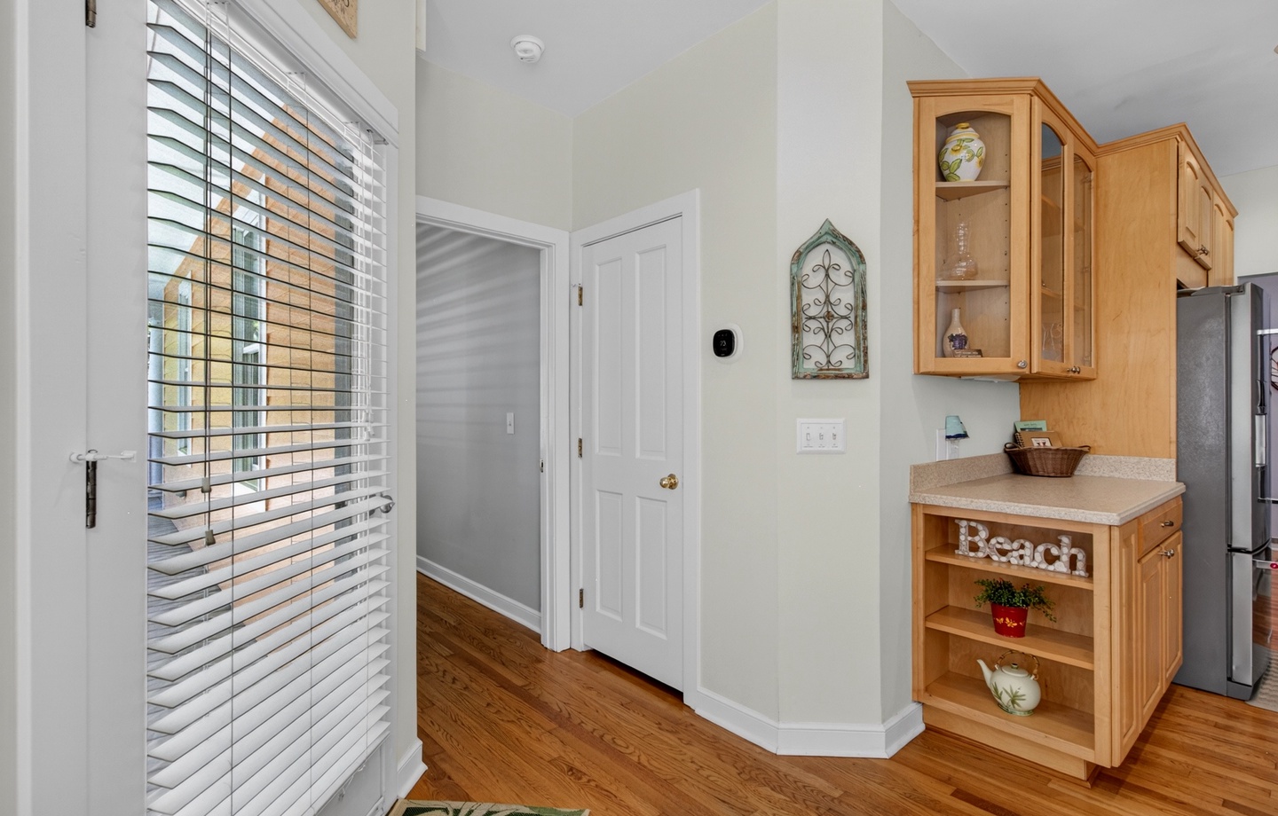 Your bright kitchen welcomes you with warm wood cabinetry, coastal charm, and plenty of natural light streaming through plantation shutters.