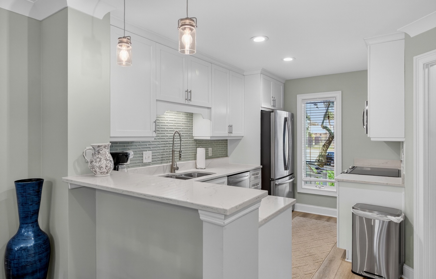 Bright, modern kitchen featuring white cabinetry, gleaming countertops, and stainless appliances—your perfect space to create delicious meals during your stay.