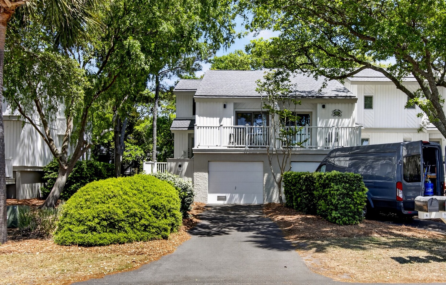 Modern two-story vacation home nestled among mature trees with convenient parking and welcoming balconies.