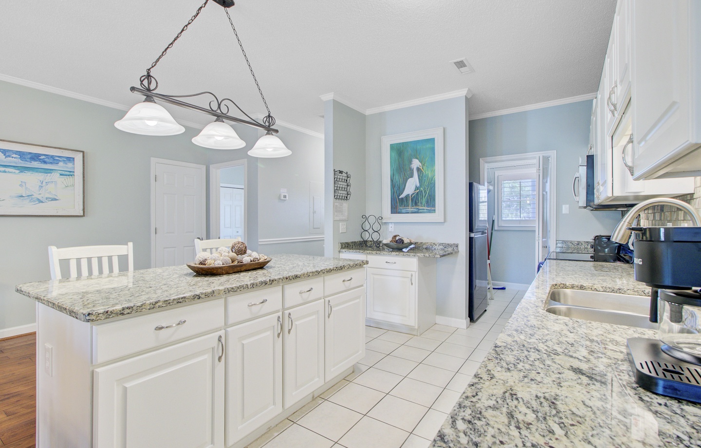 Cook with ease in your spacious coastal kitchen, featuring granite countertops and elegant lighting perfect for meal preparation.