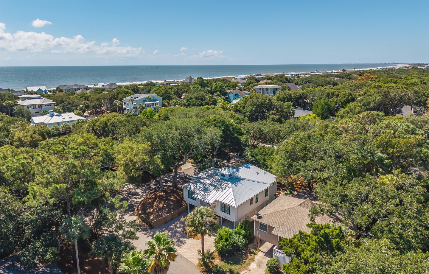 This coastal property sits nestled among lush greenery with the sparkling ocean just beyond, offering a peaceful retreat surrounded by natural beauty and nearby beach access.