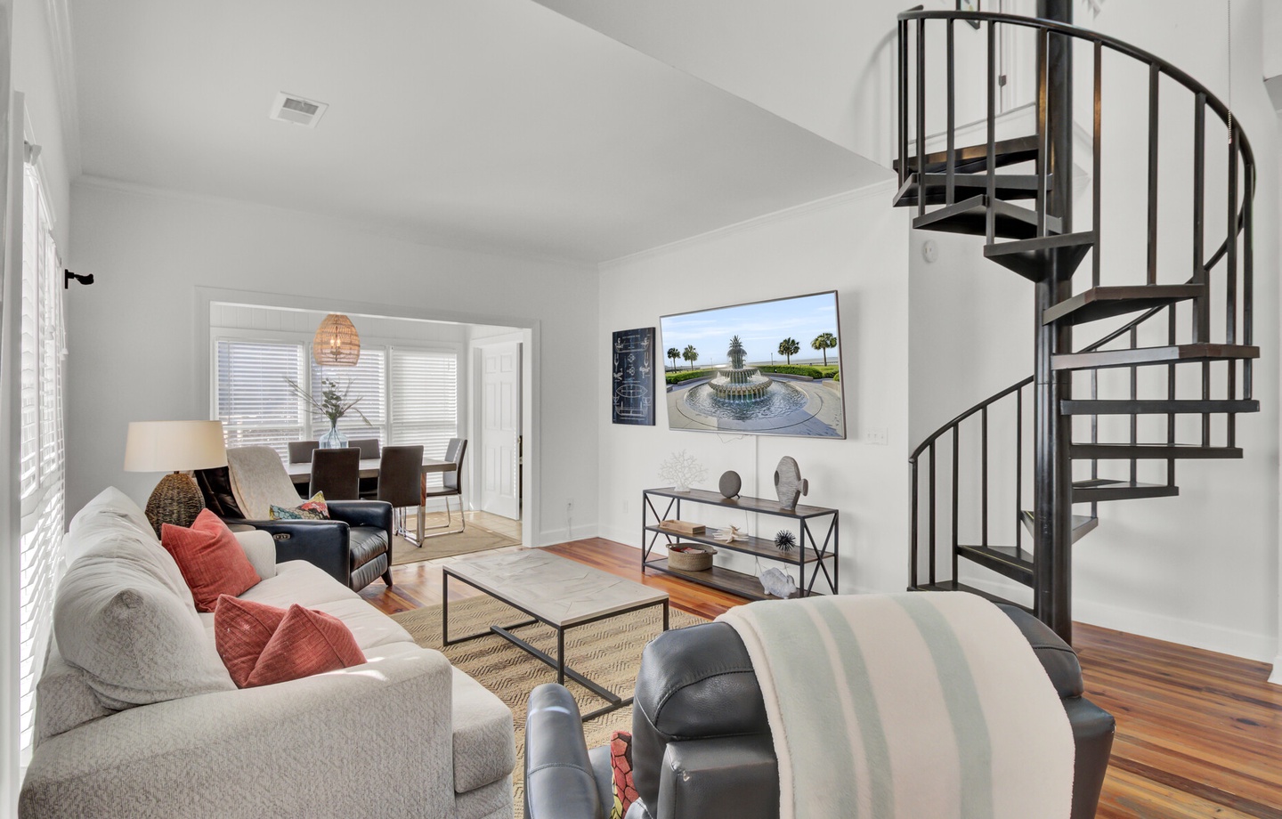 Relax in your bright living space featuring a striking spiral staircase, cozy seating, and modern style throughout.