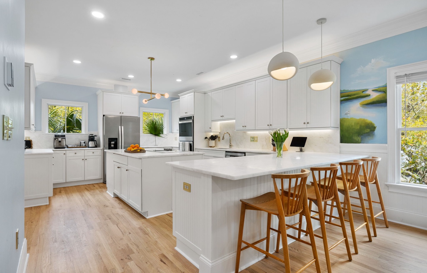 Gather around your spacious kitchen island while sunlight streams through windows. White cabinetry and warm wood floors create the perfect backdrop for memorable meals.