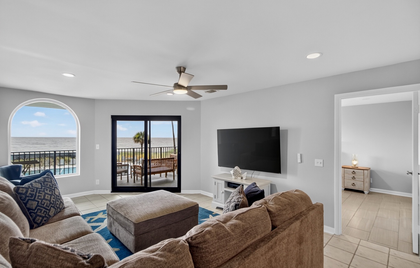 Settle into your oceanfront retreat with plush seating, a ceiling fan, and balcony doors opening to panoramic views. Your coastal escape awaits just steps away.