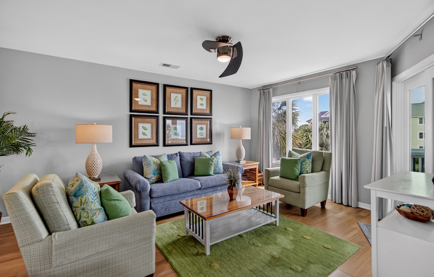 Unwind in this inviting living space with soft seating, tropical touches, and natural light streaming through palm-framed windows—your perfect coastal retreat.