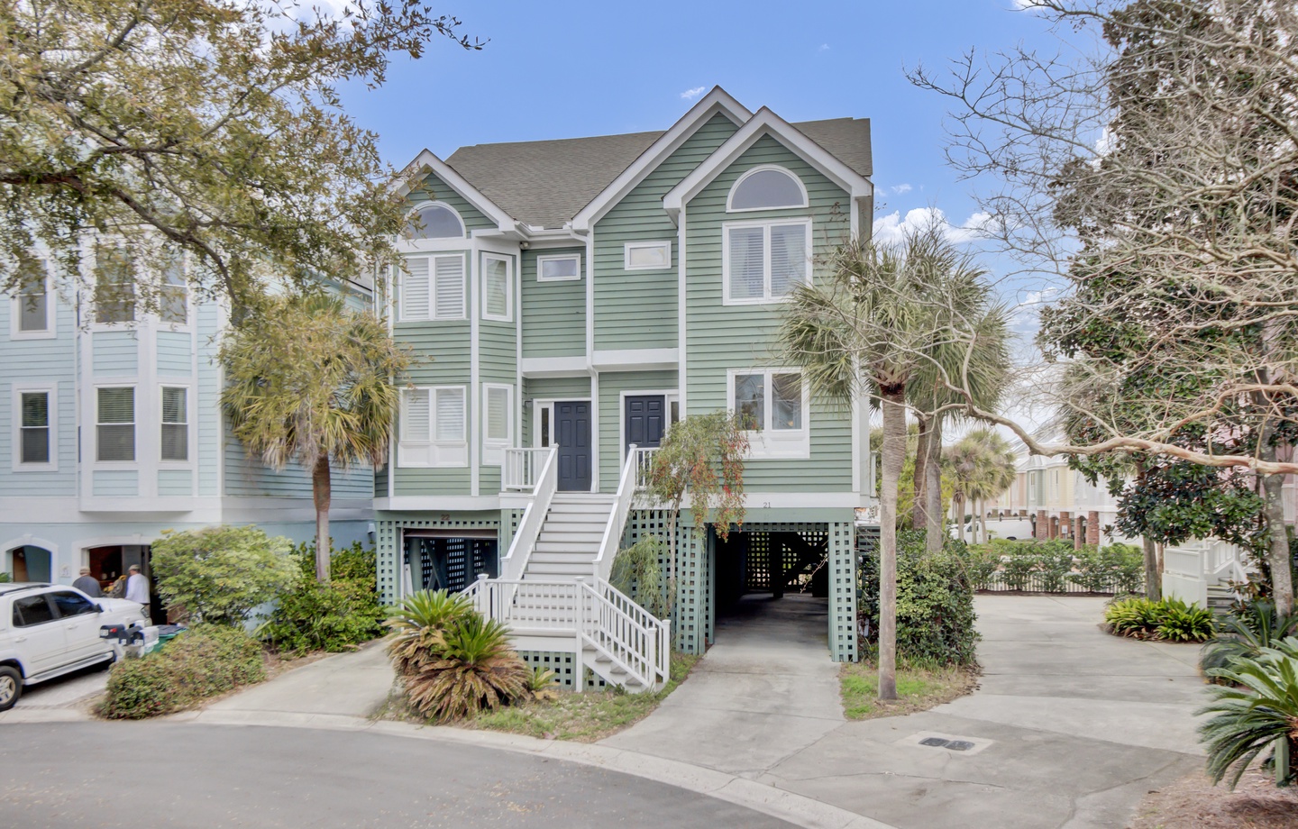 Charming coastal duplex with tropical landscaping and convenient ground-level parking in a peaceful residential setting.