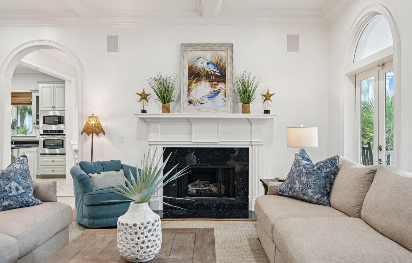 Sink into plush sofas by your elegant fireplace, where coastal artwork and soft lighting create the perfect atmosphere for relaxing evenings.