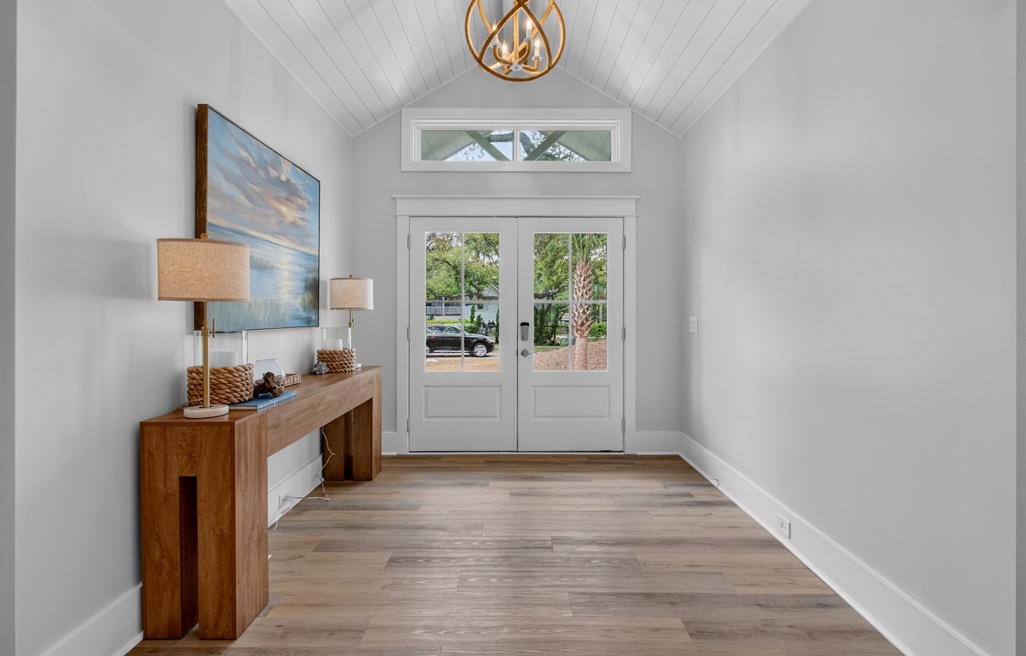 You're welcomed by soaring vaulted ceilings and warm wood floors in this elegant entryway, where natural light streams through French doors.