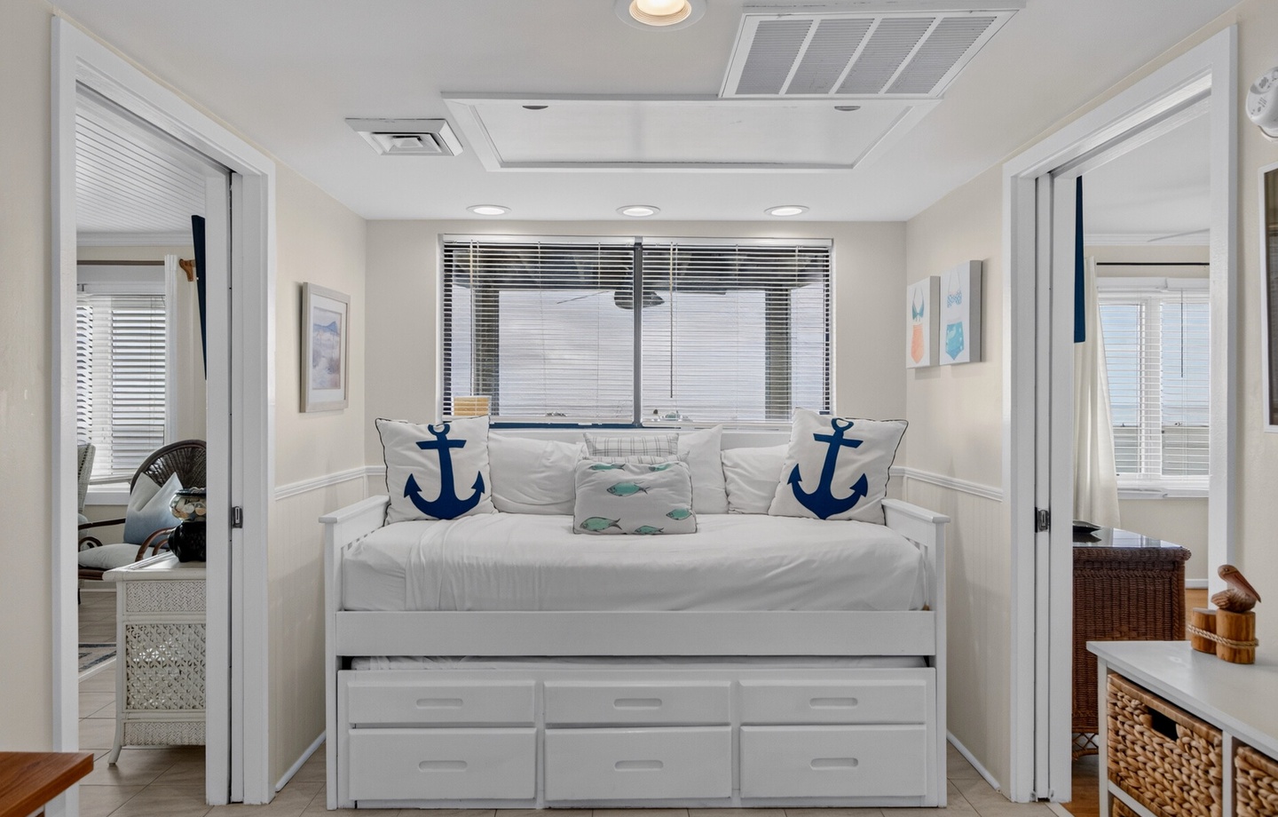 Relax in your airy coastal retreat with a nautical-inspired daybed, built-in storage, and soft natural light filtering through plantation blinds—your perfect beach house escape.