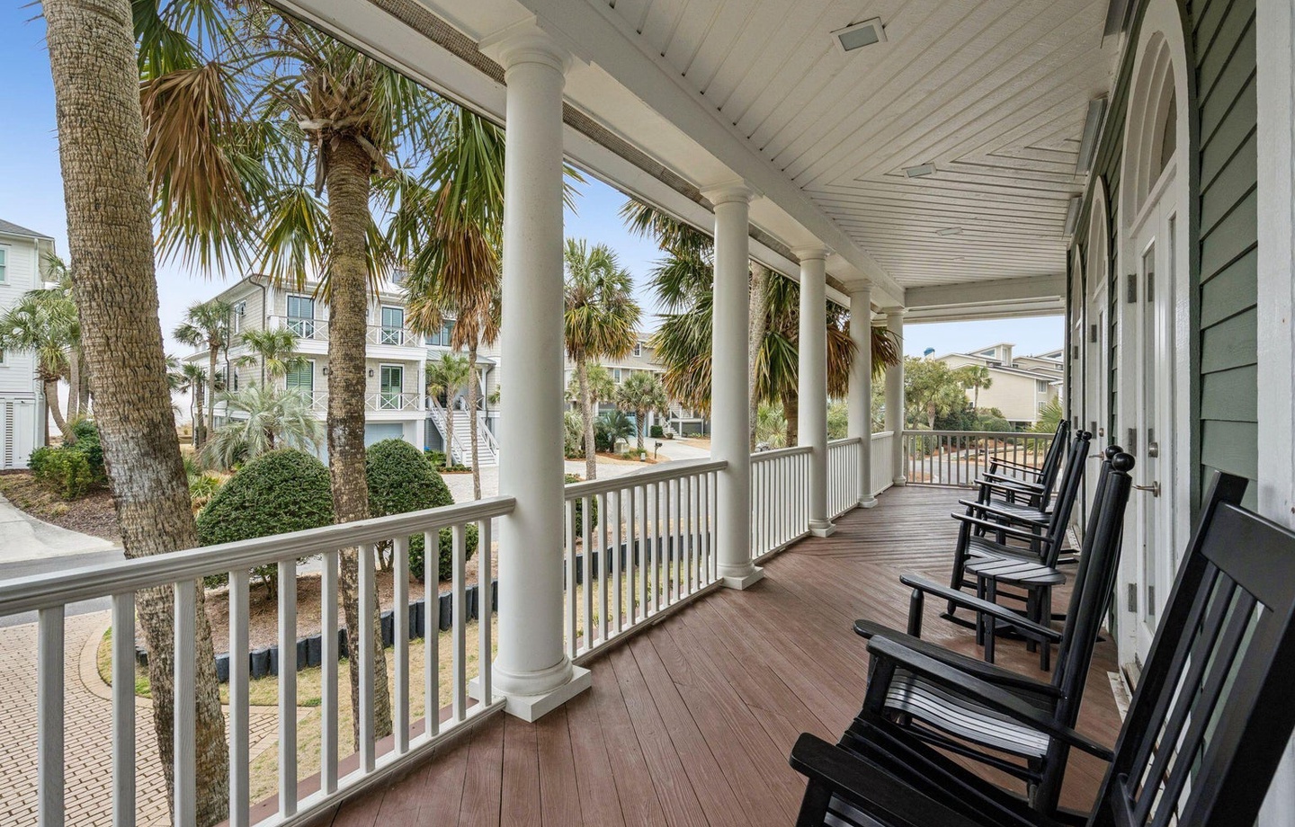 Settle into your rocking chair on this peaceful wraparound porch, where palm trees sway and coastal breezes invite you to unwind completely.