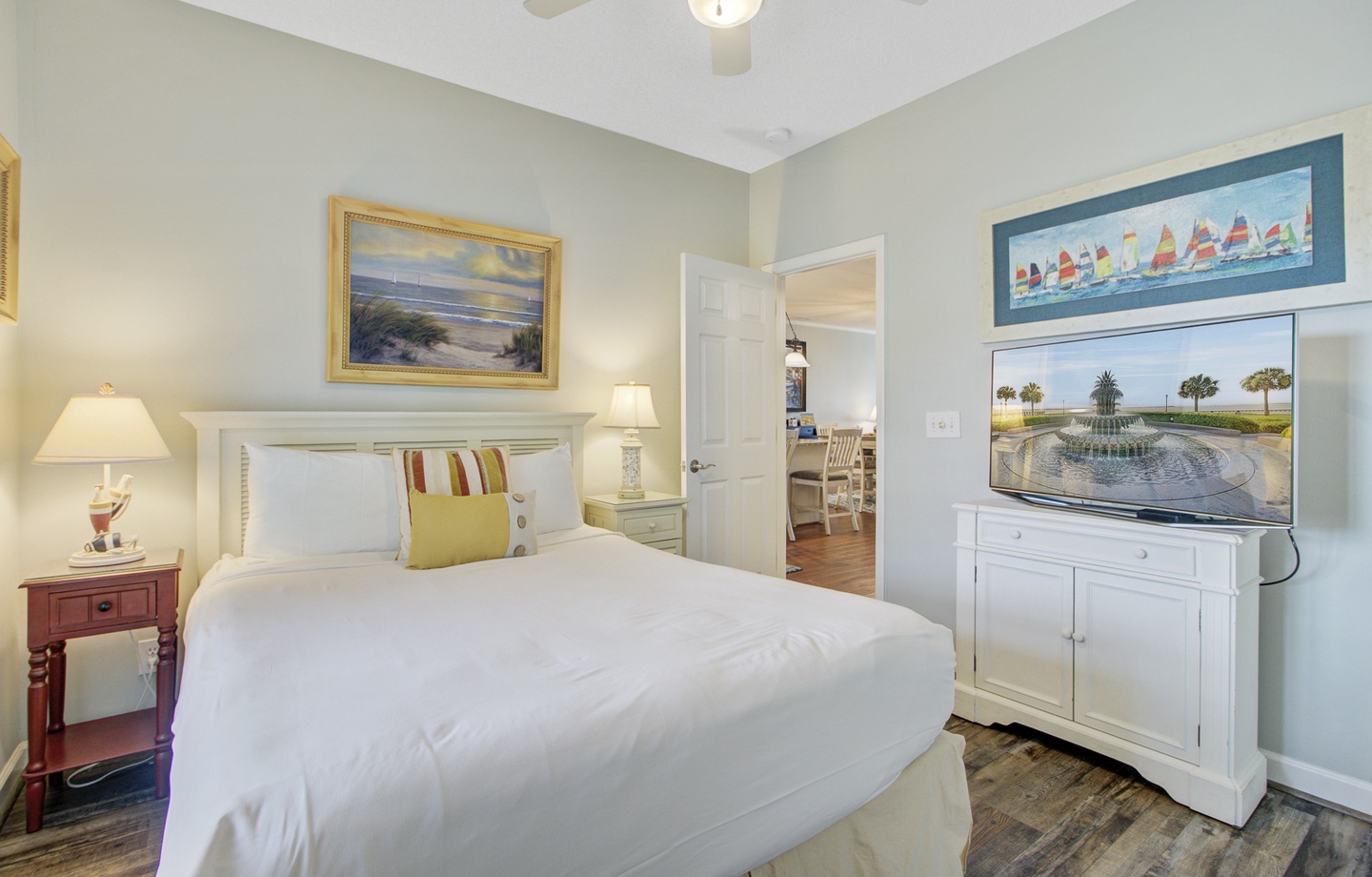 Sink into crisp white linens in your coastal-themed bedroom, where nautical artwork and warm lighting create a serene retreat after your adventures.