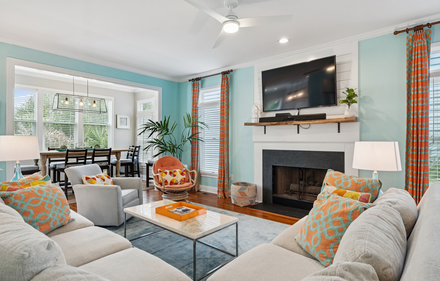 Relax in your bright, coastal-themed living space with plush seating, cozy fireplace, and cheerful orange accents throughout.