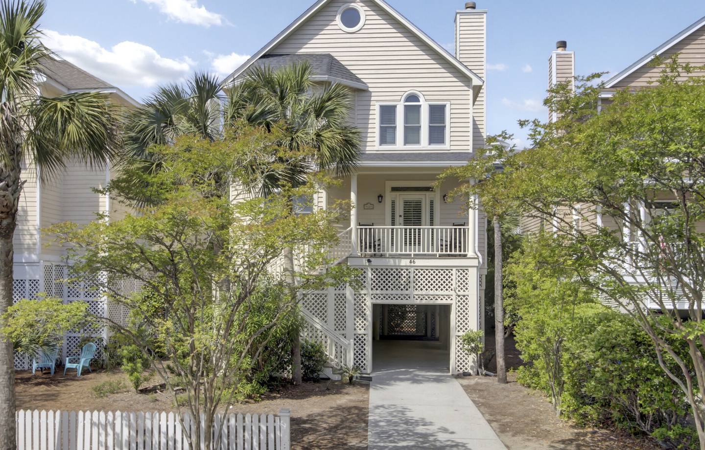 Charming coastal cottage with front porch and tropical landscaping, nestled in a peaceful residential neighborhood.