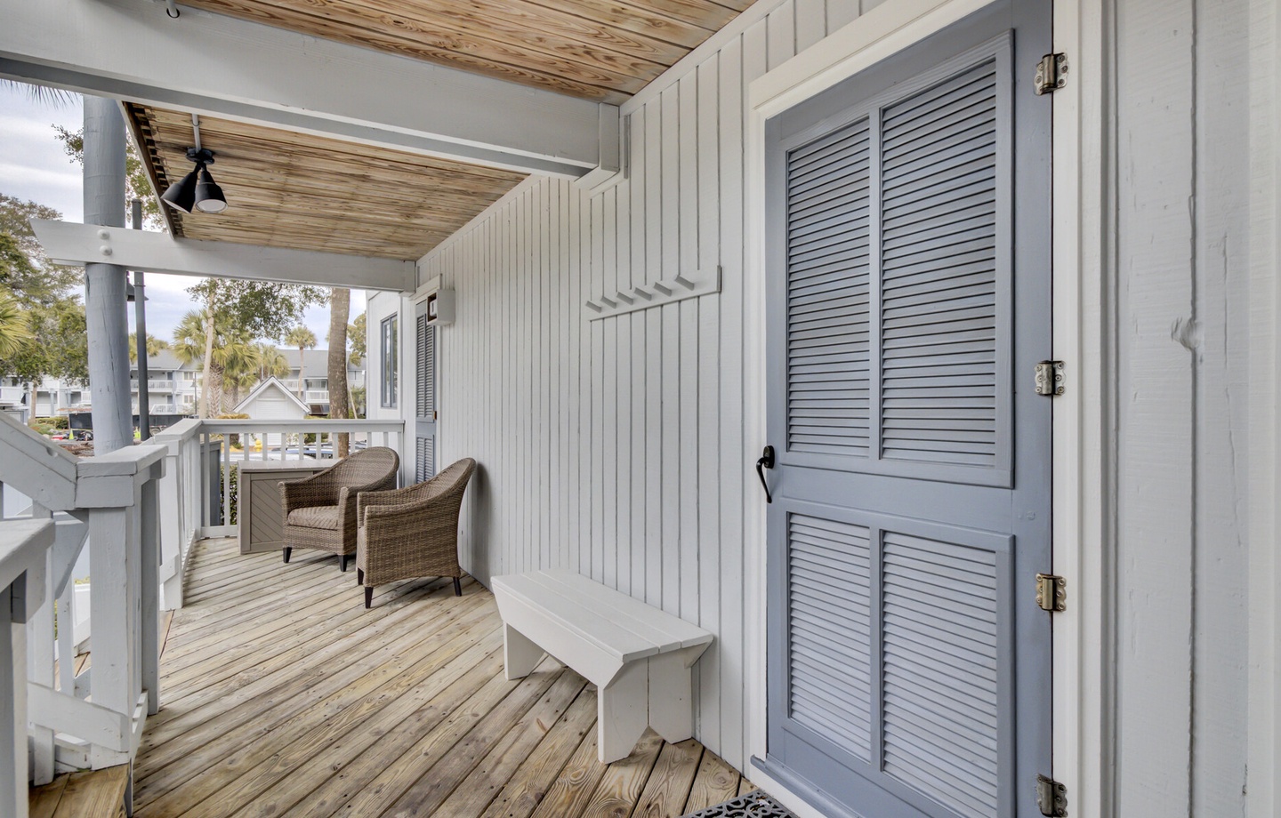 Step onto your private covered deck where wicker chairs await for morning coffee and evening relaxation in coastal comfort.