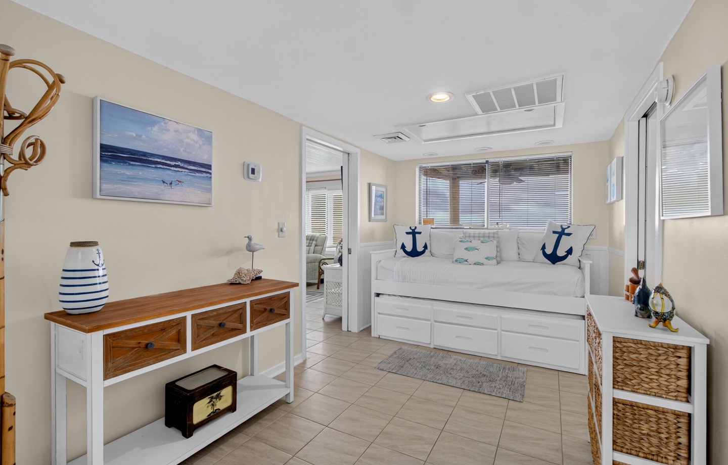 Step into your nautical-inspired retreat, where crisp whites and coastal blues create a serene atmosphere. Your daybed invites restful moments, while storage baskets and thoughtful decor bring beach charm to this bright, tile-floored sanctuary.