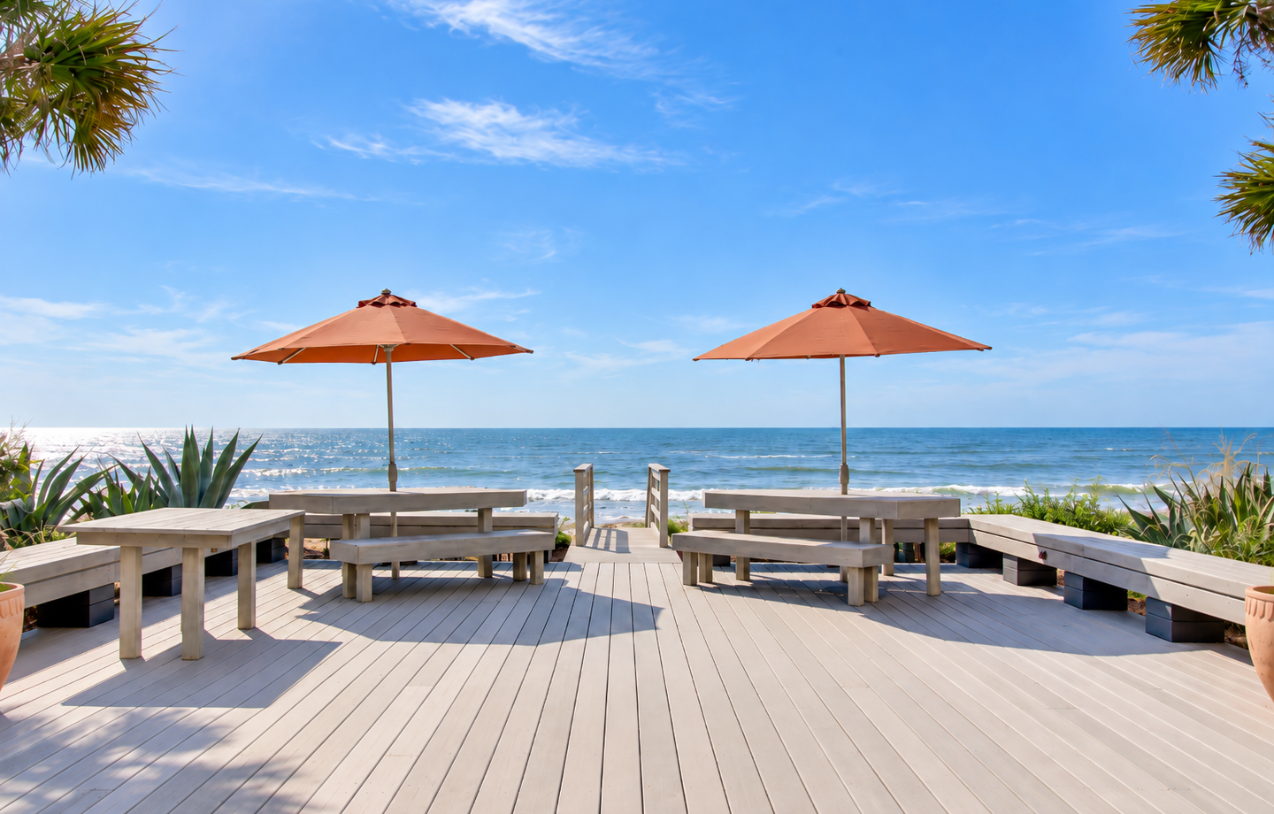 The property features a beachfront deck overlooking the ocean, with loungers and umbrellas for guests to enjoy sunny days by the shore.