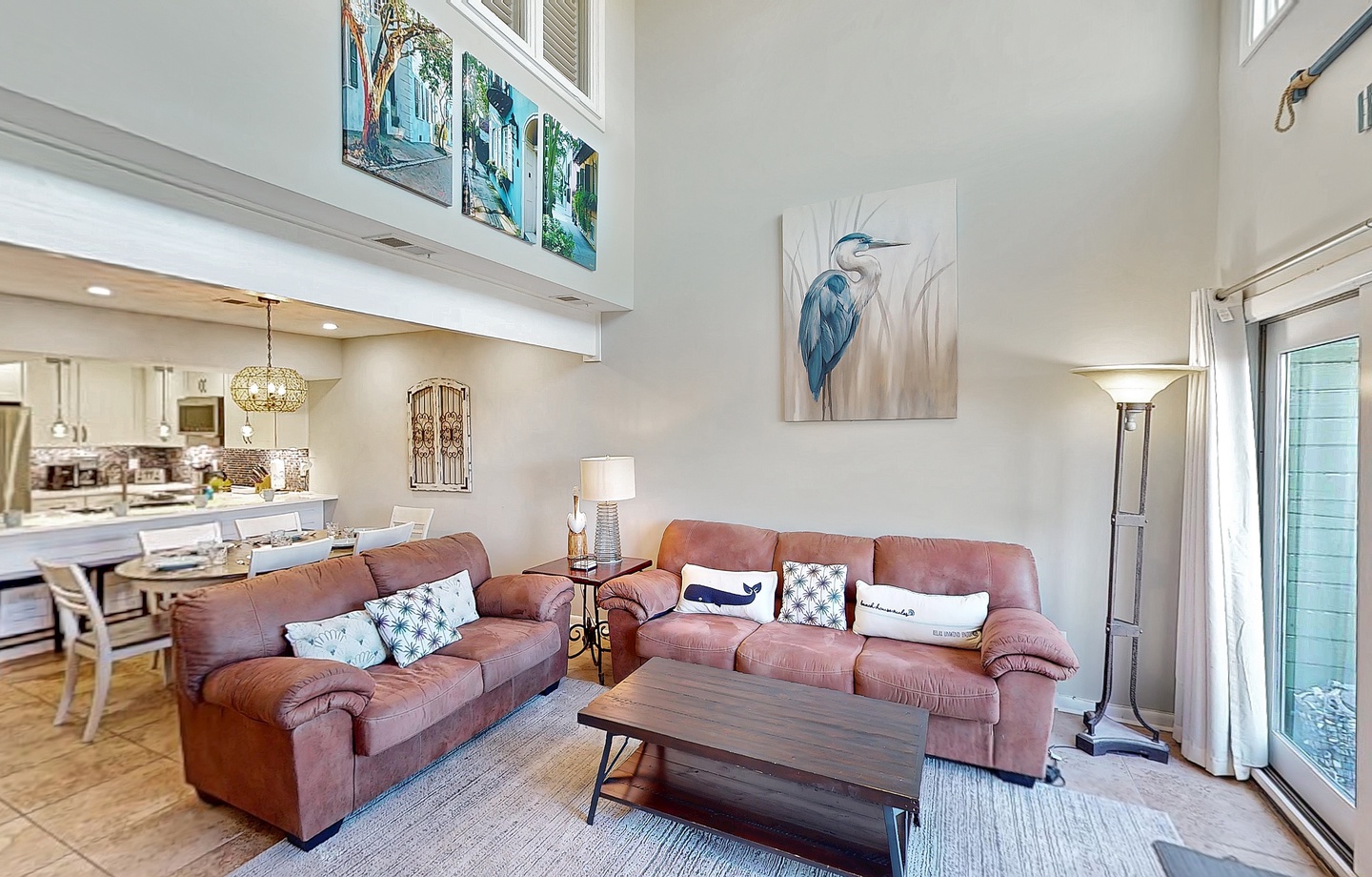 Relax in your bright, open living space with soaring ceilings, plush seating, and soft natural light. The coastal artwork adds a peaceful touch while you unwind after a day of exploring.