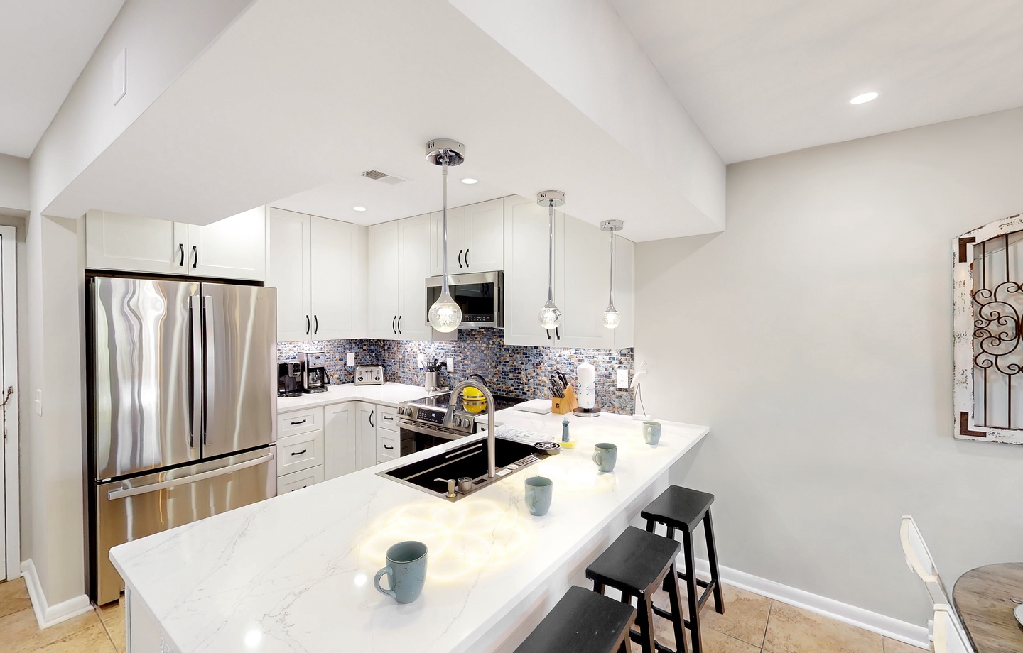 Your gourmet kitchen features sleek white cabinetry, gleaming marble countertops, and stainless steel appliances—perfect for crafting morning coffee at the island or preparing a feast under vaulted ceilings with warm pendant lighting.