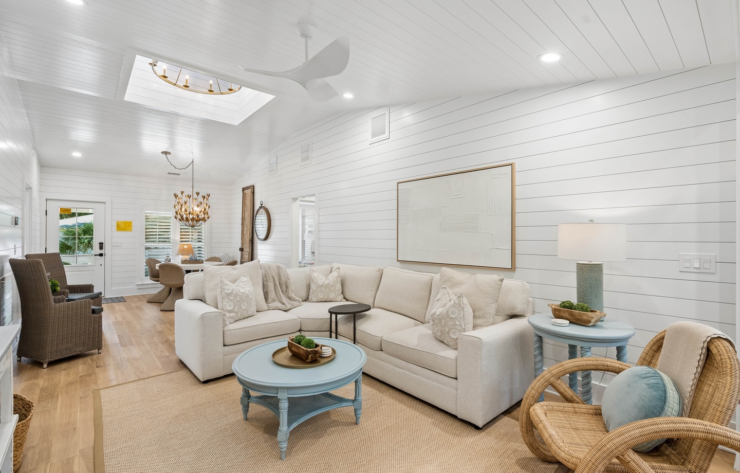 Sink into the plush sofa and unwind in this bright, airy living room with its vaulted shiplap ceilings, natural light streaming through the skylight, and coastal charm that invites you to relax.