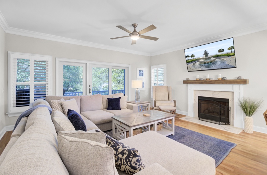 Unwind in your spacious living room featuring plush seating, a cozy fireplace, and large windows showcasing lush garden views.