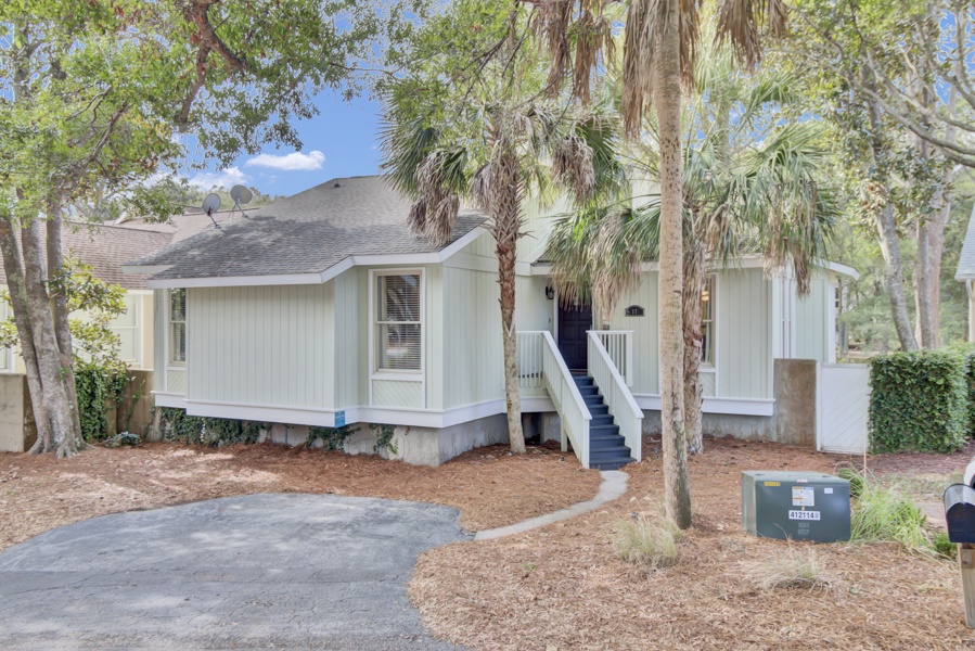 Charming coastal cottage nestled among towering palms and mature trees, offering a peaceful retreat with convenient parking.